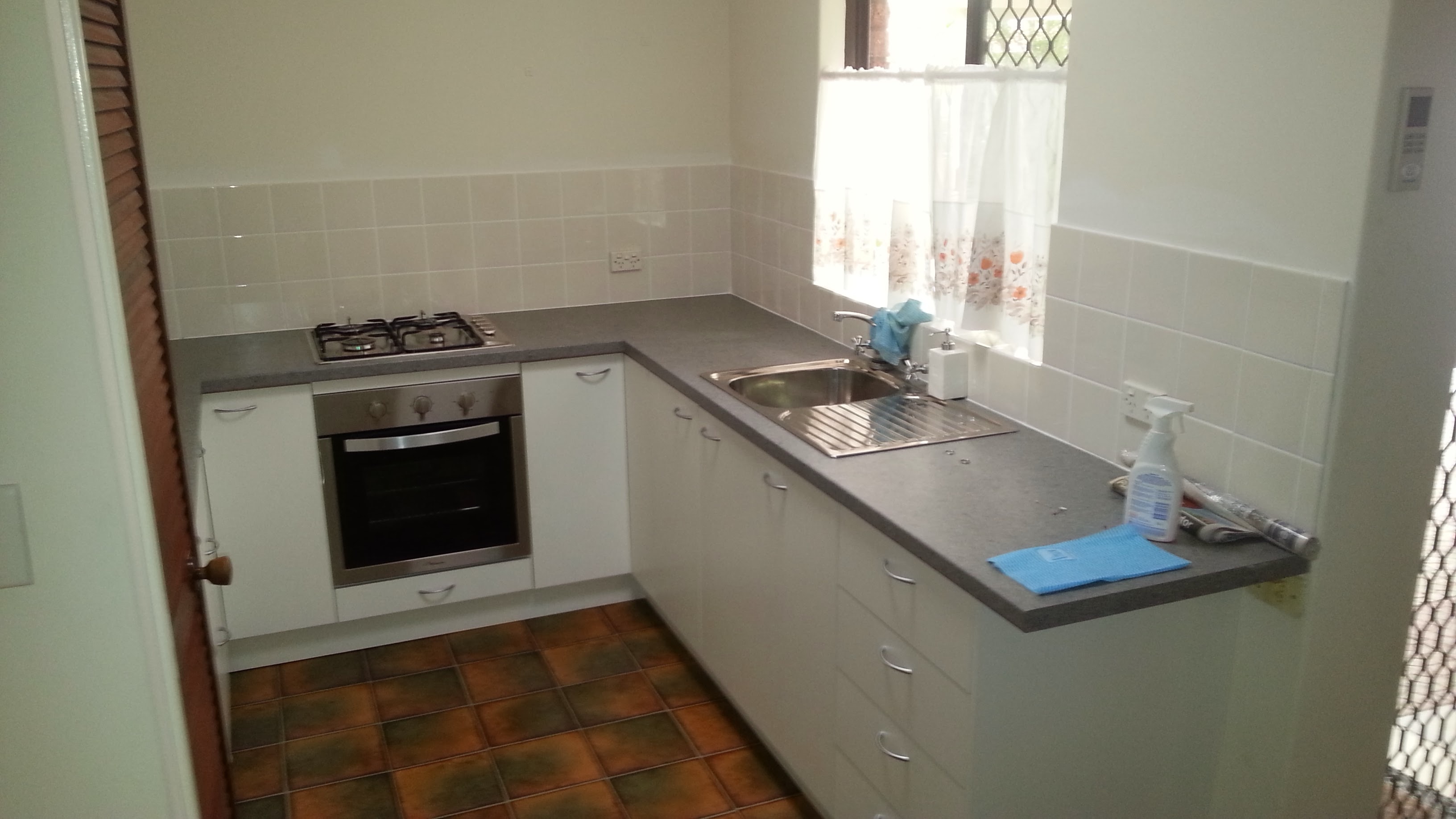 Compact white kitchen with gas cooktop and stainless steel oven