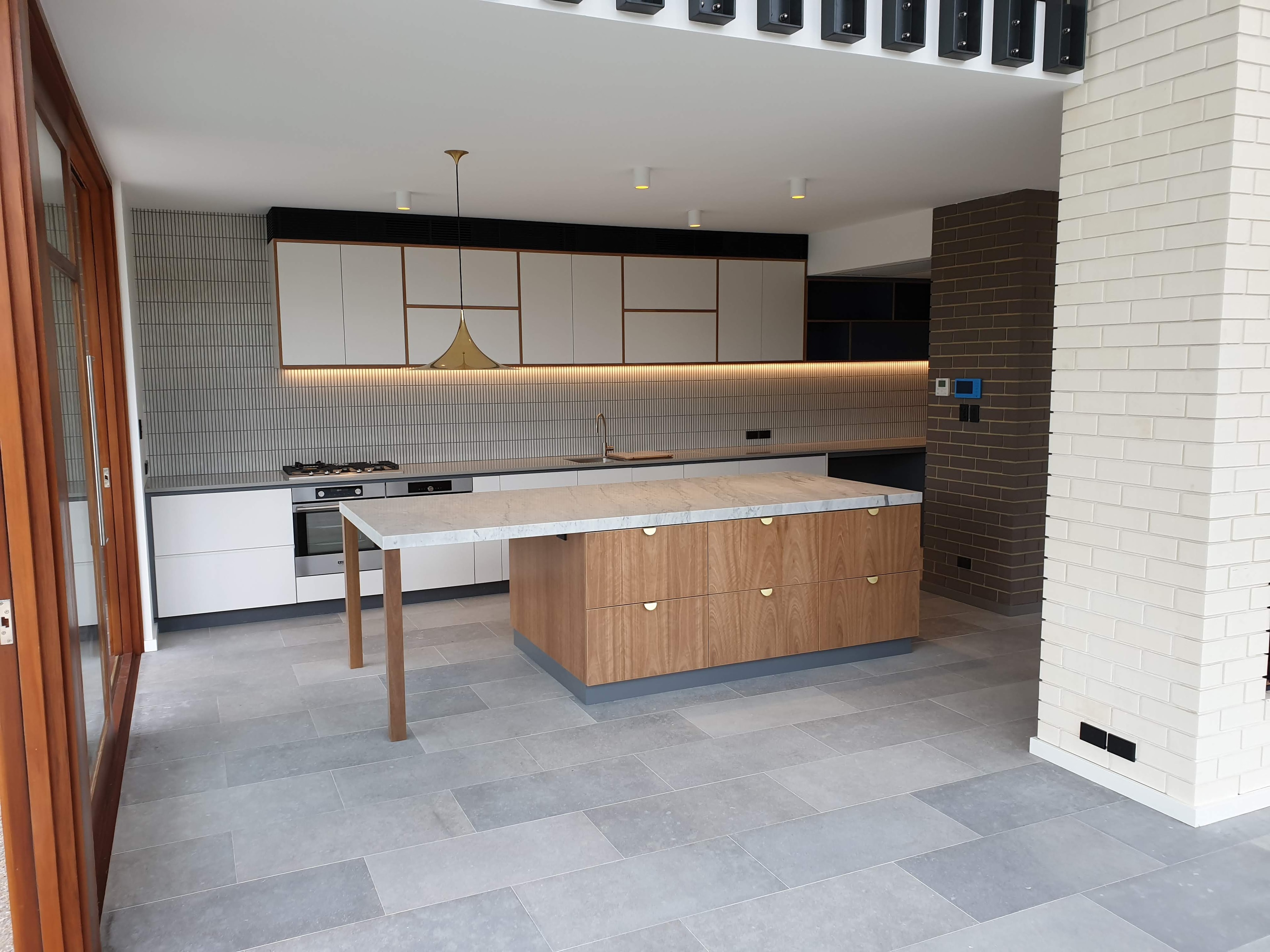 Two-tone kitchen with timber island marble benchtop and brass hardware